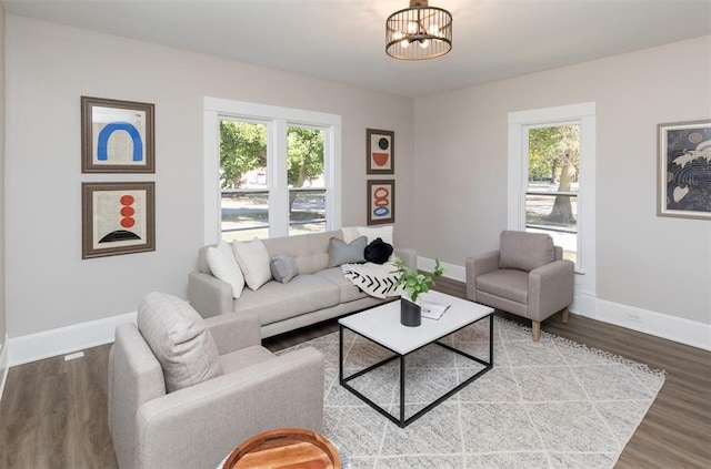 living area featuring a chandelier, wood finished floors, and baseboards