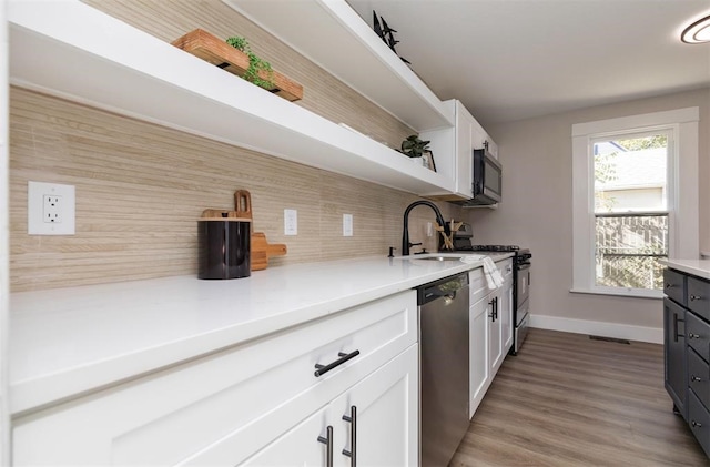 kitchen with stainless steel appliances, a sink, white cabinets, backsplash, and open shelves