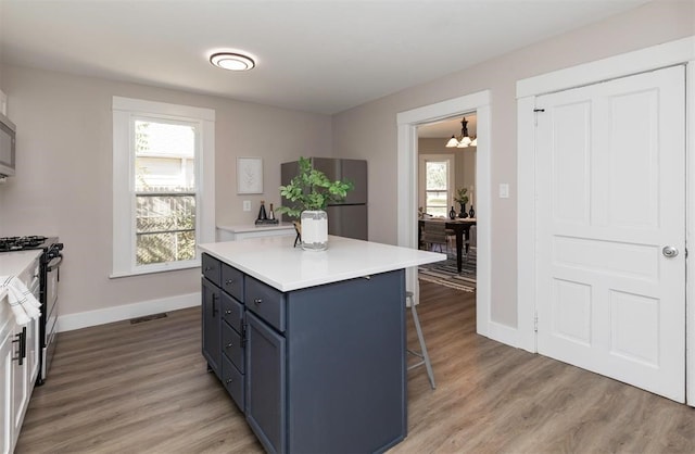 kitchen featuring a kitchen island, appliances with stainless steel finishes, light countertops, light wood-style floors, and a kitchen bar