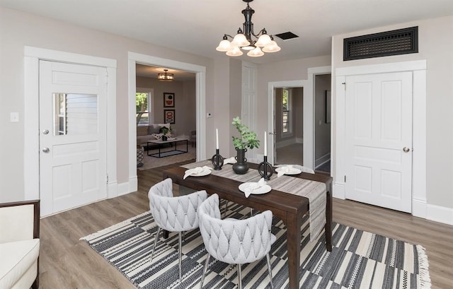 dining space with baseboards, visible vents, a chandelier, and wood finished floors