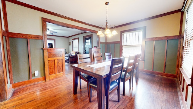 dining area featuring ornamental molding, hardwood / wood-style floors, and ceiling fan with notable chandelier