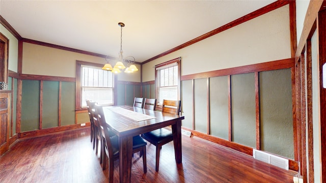 dining area featuring crown molding, a chandelier, and dark hardwood / wood-style flooring