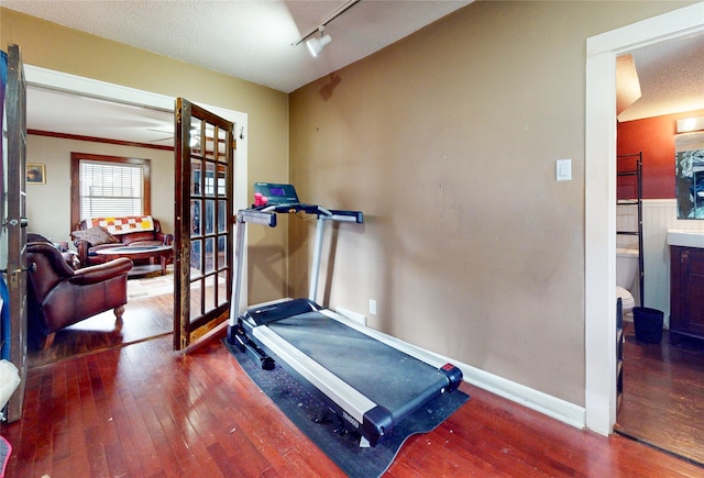 workout room with a textured ceiling, track lighting, and wood-type flooring