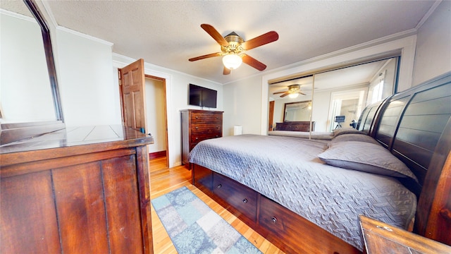 bedroom featuring a closet, crown molding, light wood-type flooring, and ceiling fan