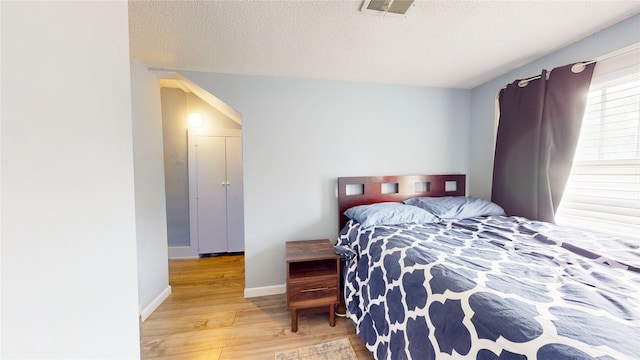 bedroom with a textured ceiling and light hardwood / wood-style flooring