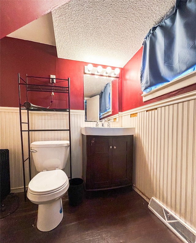 bathroom featuring hardwood / wood-style floors, a textured ceiling, toilet, wood walls, and vanity