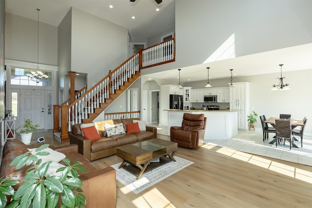 living area featuring a chandelier, recessed lighting, a high ceiling, stairway, and light wood-type flooring