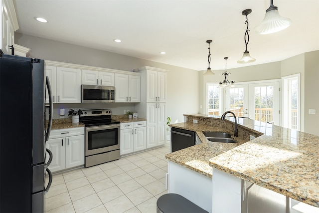 kitchen with white cabinetry, stainless steel appliances, a sink, and decorative light fixtures