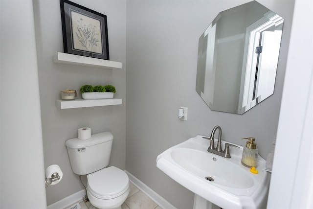 bathroom with toilet, baseboards, a sink, and tile patterned floors