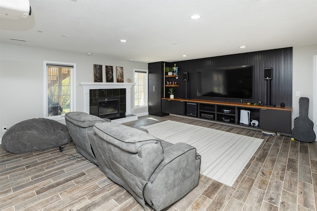 living room featuring a healthy amount of sunlight, recessed lighting, a tile fireplace, and wood finish floors