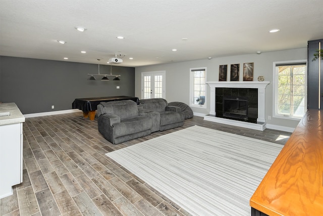 living room featuring baseboards, wood finished floors, pool table, french doors, and a fireplace