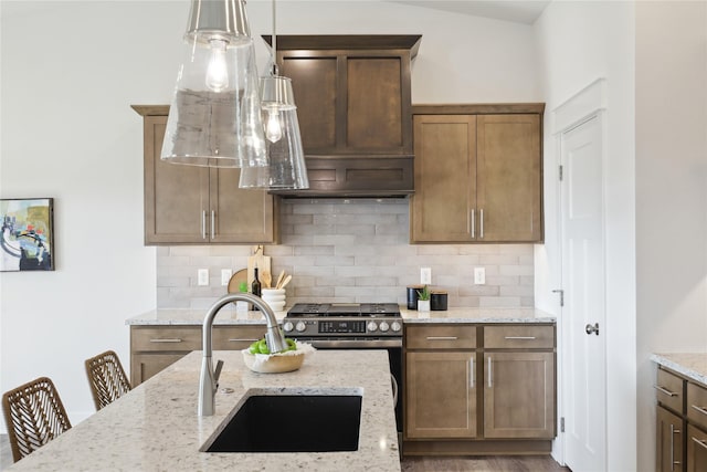 kitchen featuring decorative backsplash, light stone counters, sink, and hanging light fixtures