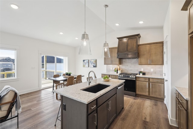 kitchen featuring sink, backsplash, an island with sink, appliances with stainless steel finishes, and custom exhaust hood