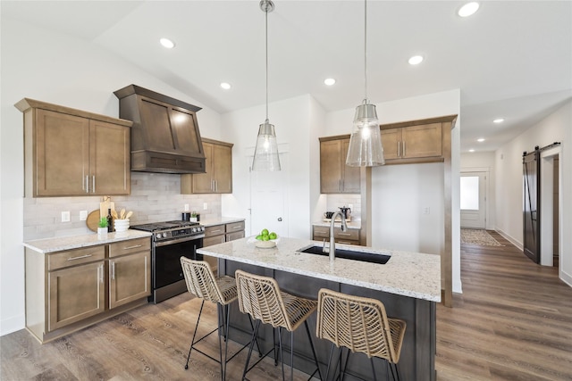 kitchen with light stone counters, vaulted ceiling, sink, a barn door, and stainless steel gas stove