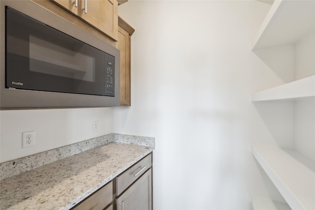 kitchen featuring black microwave and light stone counters