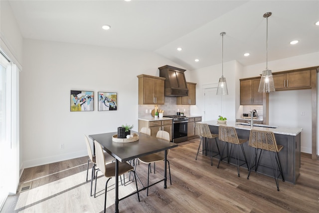 dining room featuring wood-type flooring, sink, and vaulted ceiling