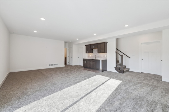 unfurnished living room with light colored carpet and sink