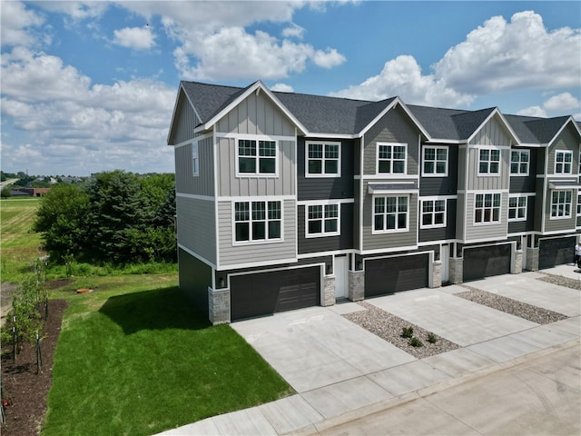 multi unit property featuring a garage, a front yard, board and batten siding, and stone siding