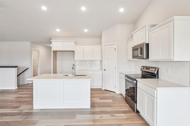 kitchen with sink, white cabinets, tasteful backsplash, a center island with sink, and appliances with stainless steel finishes