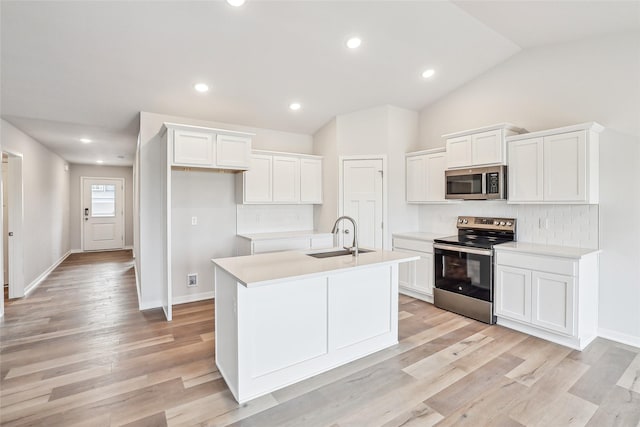 kitchen with stainless steel appliances, an island with sink, lofted ceiling, white cabinets, and sink