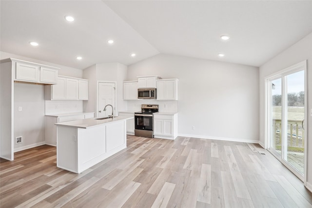 kitchen featuring stainless steel appliances, white cabinetry, sink, and an island with sink