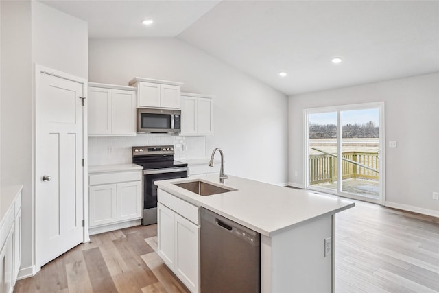 kitchen with a kitchen island with sink, backsplash, white cabinets, appliances with stainless steel finishes, and sink