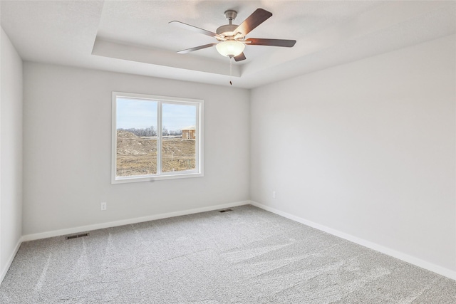 carpeted empty room featuring ceiling fan and a tray ceiling