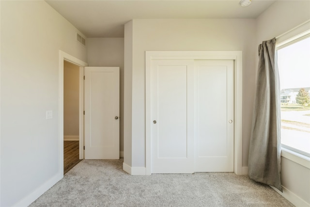 unfurnished bedroom with multiple windows, a closet, and light colored carpet