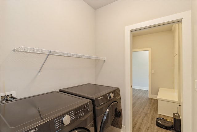 laundry area with washing machine and clothes dryer and light wood-type flooring