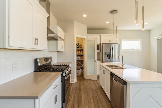 kitchen featuring a center island with sink, appliances with stainless steel finishes, white cabinetry, sink, and decorative light fixtures