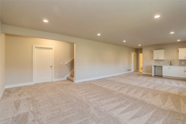 unfurnished living room featuring sink and light colored carpet