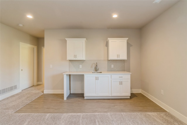 kitchen with white cabinetry, backsplash, sink, and light wood-type flooring