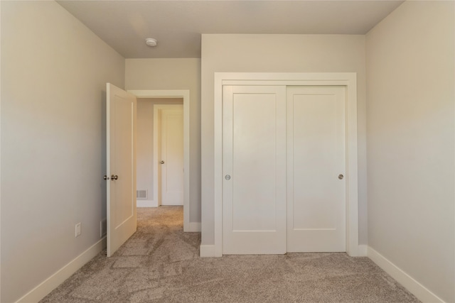 unfurnished bedroom with a closet and light colored carpet