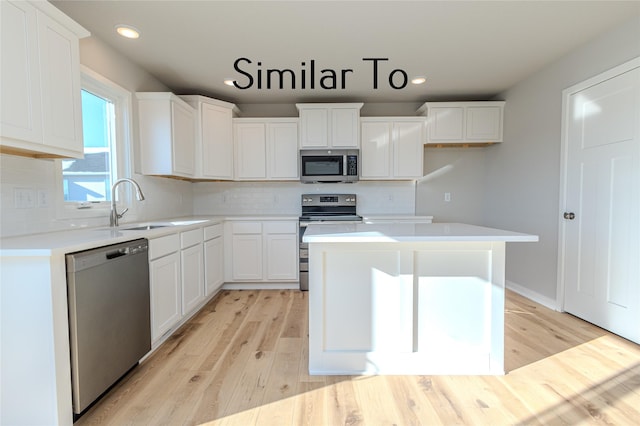 kitchen featuring stainless steel appliances, light countertops, a kitchen island, and white cabinetry