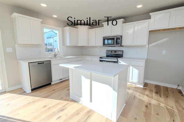 kitchen featuring stainless steel appliances, light countertops, a sink, and white cabinetry