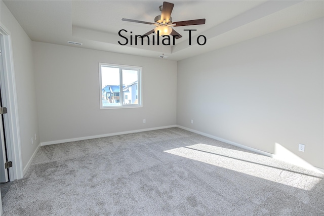 empty room featuring light colored carpet, a raised ceiling, visible vents, and baseboards