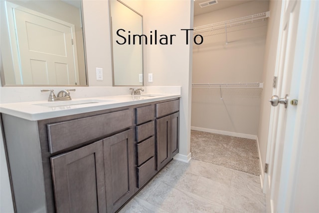 bathroom with visible vents, a sink, baseboards, and double vanity