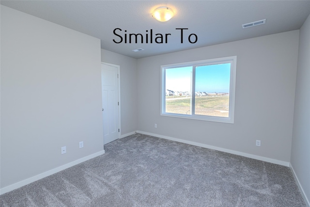 carpeted spare room featuring visible vents and baseboards