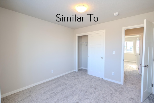 unfurnished bedroom with a closet, light carpet, and baseboards