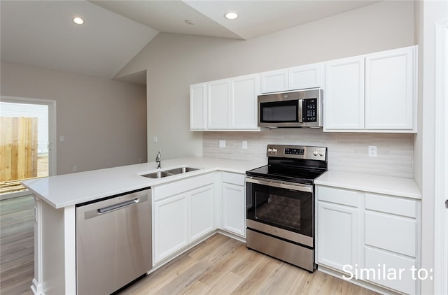 kitchen with sink, backsplash, kitchen peninsula, stainless steel appliances, and vaulted ceiling