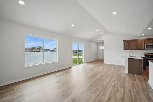 kitchen featuring recessed lighting, stainless steel appliances, vaulted ceiling, light countertops, and open floor plan