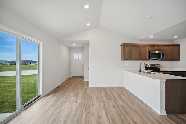 kitchen featuring light wood-style flooring, a sink, stainless steel appliances, light countertops, and vaulted ceiling