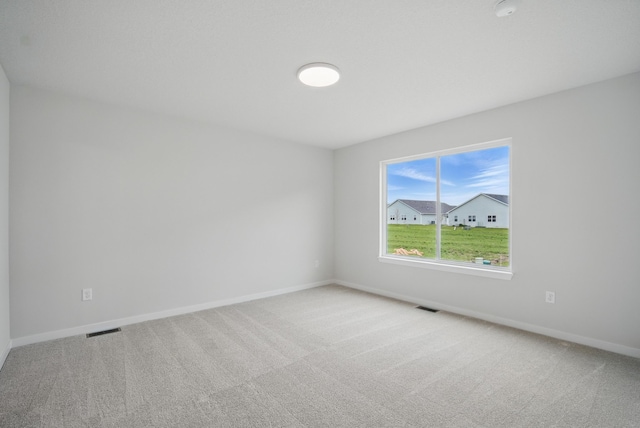 carpeted spare room with baseboards and visible vents