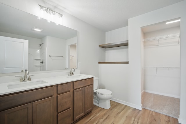 full bathroom featuring walk in shower, toilet, a sink, and wood finished floors