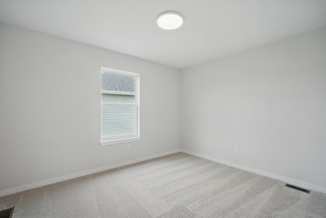 carpeted empty room featuring visible vents and baseboards