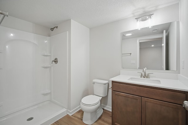 bathroom featuring a textured ceiling, walk in shower, toilet, wood finished floors, and vanity
