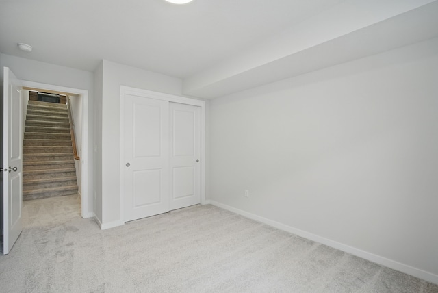 unfurnished bedroom featuring baseboards, carpet floors, and a closet