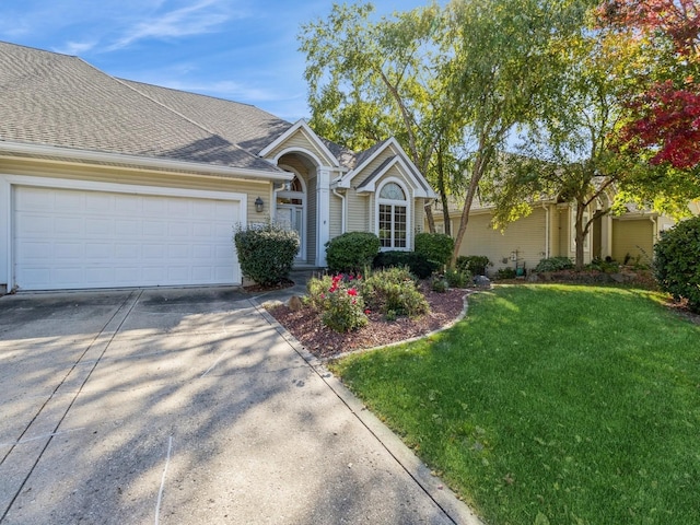 view of front facade with a garage, concrete driveway, a front lawn, and a shingled roof