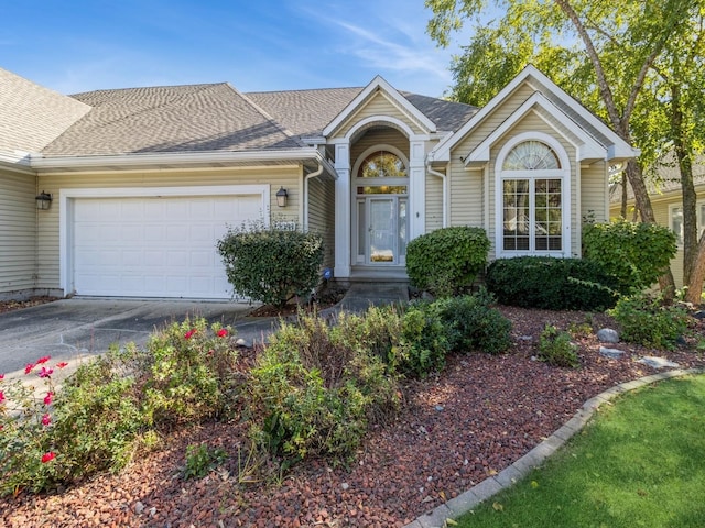 single story home featuring driveway, a shingled roof, and a garage