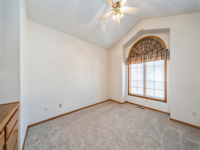 spare room with visible vents, a ceiling fan, baseboards, lofted ceiling, and light colored carpet